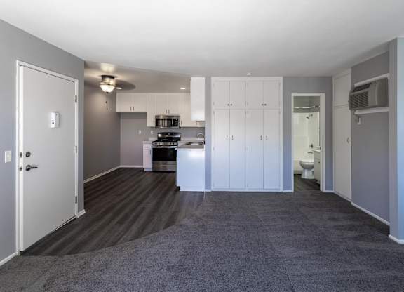 A spacious kitchen with white cabinets and a white door.