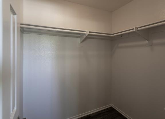 A white closet with a shelf and a door.