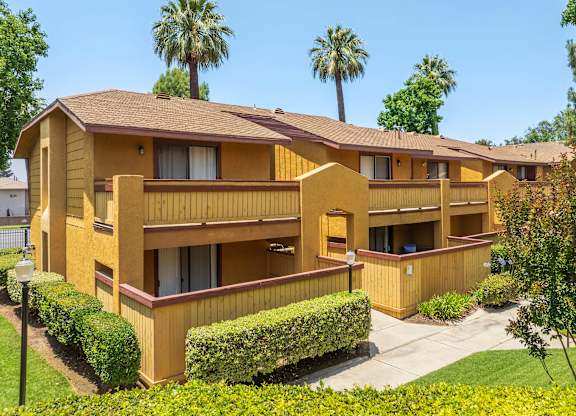 A yellow building with a brown roof and a green lawn in front.