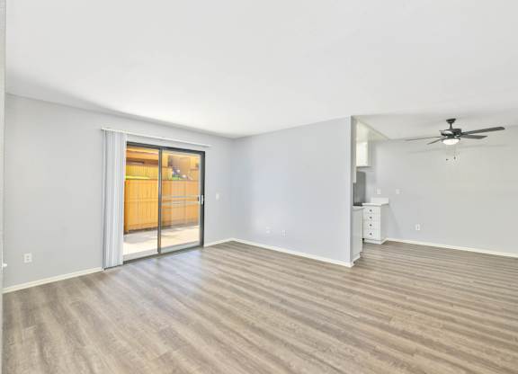 A room with a ceiling fan and a wooden floor.