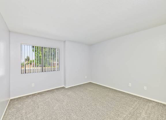 A room with a window and a carpeted floor.