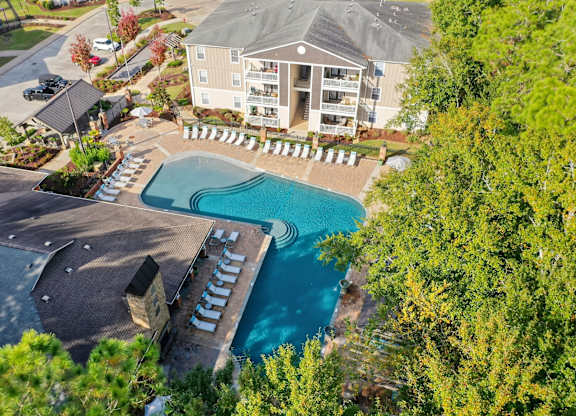 A large swimming pool surrounded by a concrete patio and a small building.