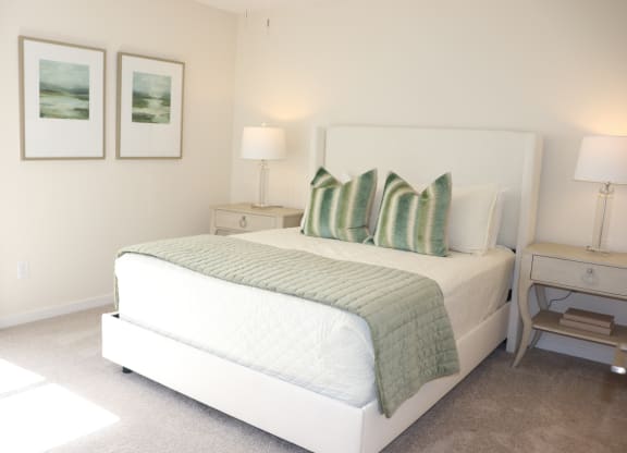 a bedroom with a bed and two pictures on the wall at The Vineyard at Castlewoods Apartment Homes in Brandon, MS 39047