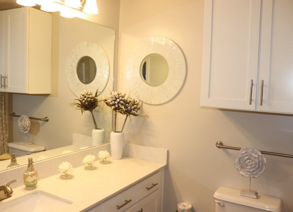a bathroom with two mirrors and a sink and a toilet  at Laurelwood Apartment Homes, Mississippi, 39440