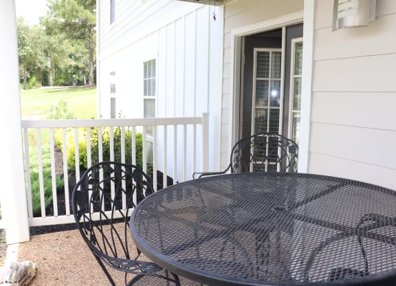 a patio with a table and chairs in front of a house  at Laurelwood Apartment Homes, Mississippi