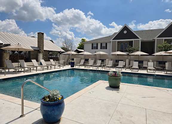 A pool area with a blue pot in the foreground and a building in the background.