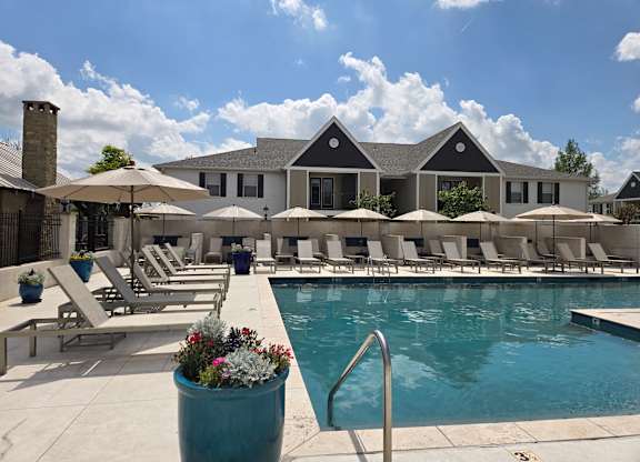 A pool area with sun loungers and a building in the background.