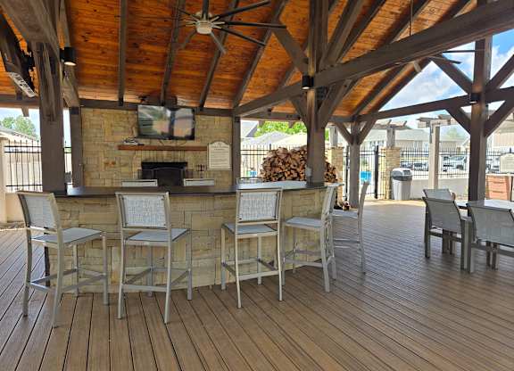 A wooden deck with a bar and chairs.