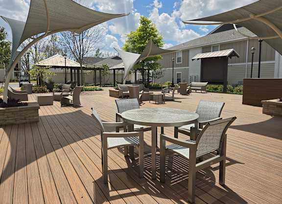 A wooden deck with a table and chairs under a canopy.