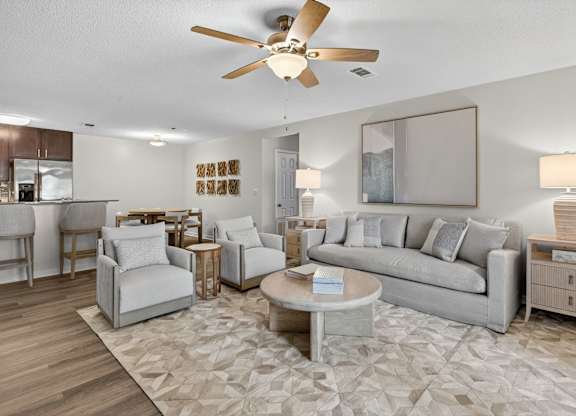 A living room with a grey couch, a coffee table, and a ceiling fan.