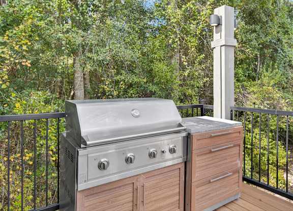 A stainless steel grill is on a wooden deck.