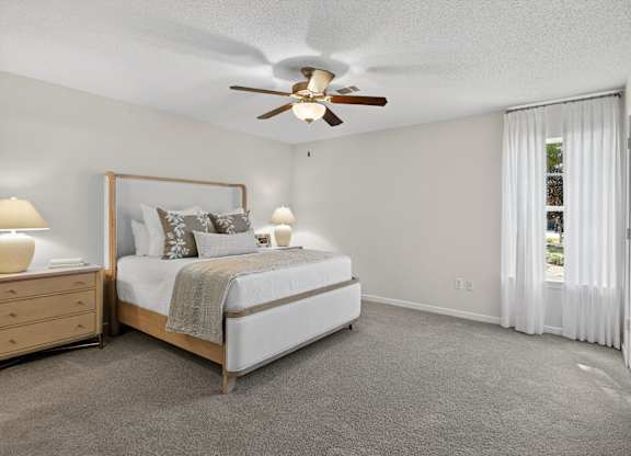 A bedroom with a bed, dresser, and ceiling fan.