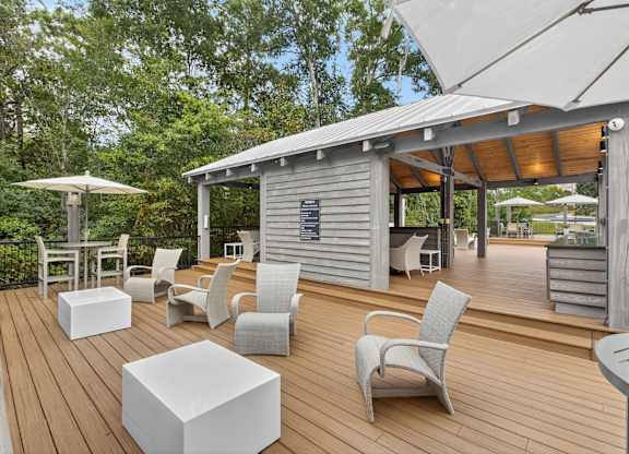 A wooden deck with white chairs and tables.