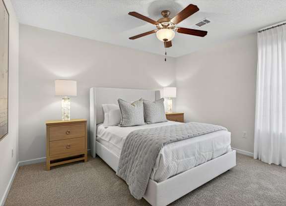A bedroom with a bed, nightstand, and a ceiling fan.