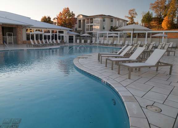 A large outdoor swimming pool with sun loungers and a building in the background. at The Azul Apartment Homes, Oxford, Mississippi