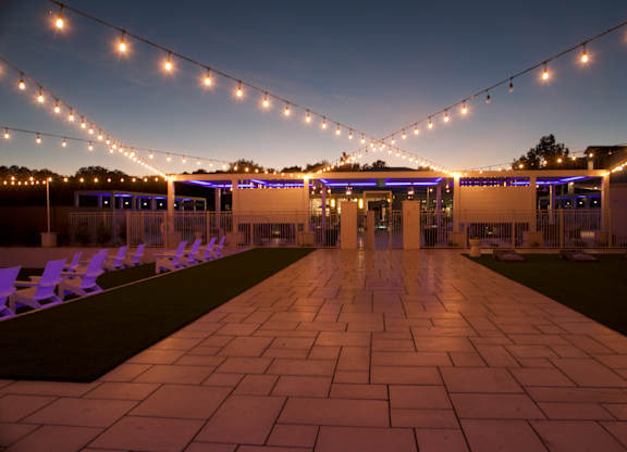 A long walkway with purple chairs and string lights on either side. at The Azul Apartment Homes, Oxford, 38655