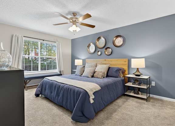 A bedroom with a bed, nightstand, and a ceiling fan.