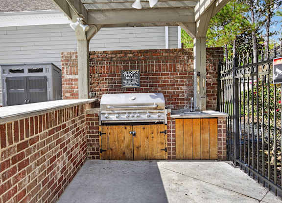 A brick wall with a grill on top and a wooden door.