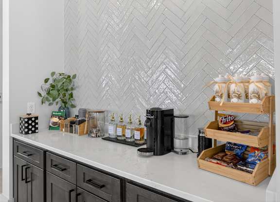 A kitchen counter with a black coffee maker and a wooden crate filled with snacks at Saltaire Apartment Homes in Santa Rosa Beach, Florida