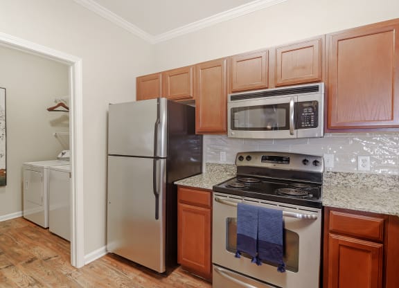 a kitchen with stainless steel appliances and wooden cabinets at Cumberland Place Apartment Homes, Tyler, TX 75703