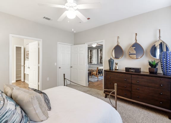 a bedroom with a bed and a dresser and a ceiling fan at Cumberland Place Apartment Homes, Texas 75703