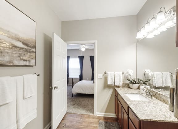 a bathroom with a mirror and a sink and a door to a bedroom at Cumberland Place Apartment Homes, Tyler, TX