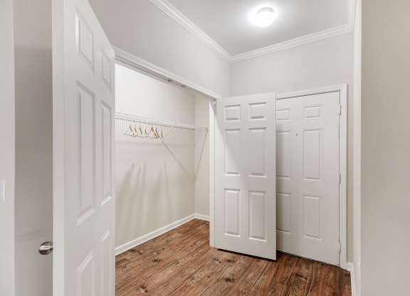 a walk in closet in a home with white walls and wood floors at Cumberland Place Apartment Homes, Tyler