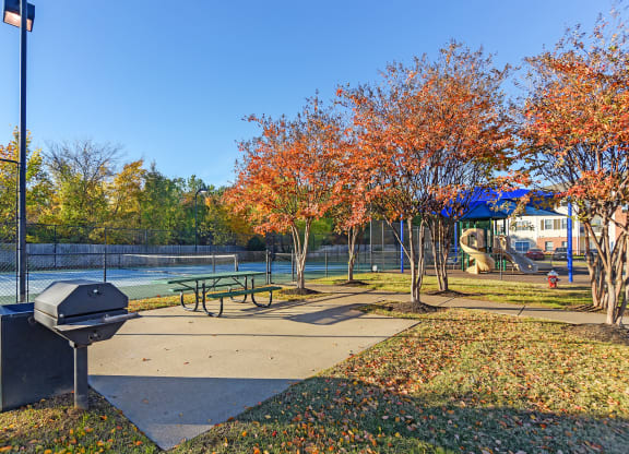 a park with a picnic table and a tennis court at Cumberland Place Apartment Homes, Tyler, TX