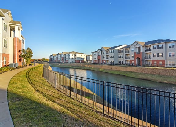 a river with a row of houses on the other side of it at Cumberland Place Apartment Homes, Texas