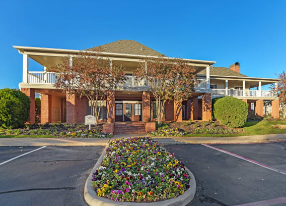 a house with a driveway and a flower garden in front of it at Cumberland Place Apartment Homes, Tyler, Texas
