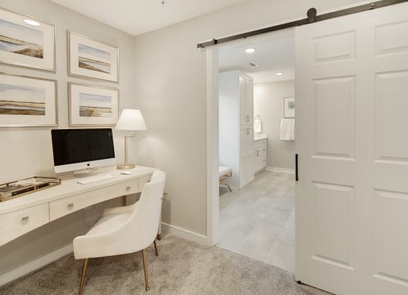 a home office with a computer desk and a door to a bathroom at The Azul Apartment Homes in MS 38655