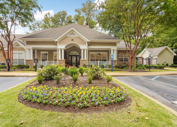 Front of a house with a flower garden in front of it at Highlands Apartment Homes, Bartlett