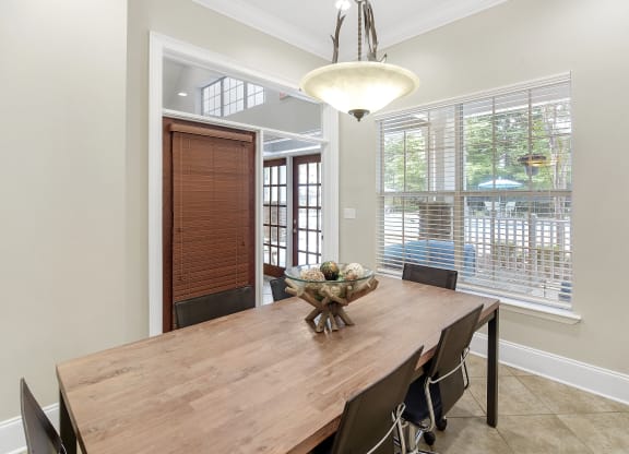 Dining room with a wooden table and chairs and a large window at Highlands Apartment Homes, Tennessee