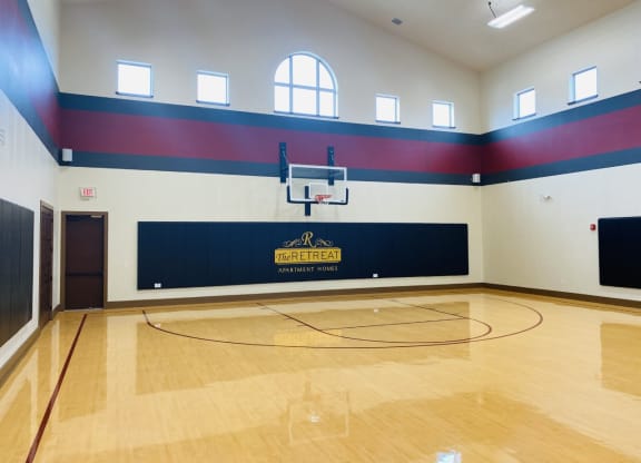 a basketball court in an empty gym with a basketball hoop at The Retreat Apartment Homes in Williston, North Dakota 58801