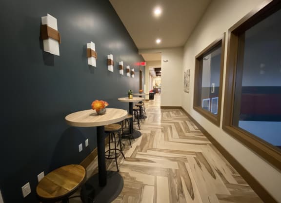 a long corridor with tables and chairs and a large window at The Retreat Apartment Homes in Williston, ND 