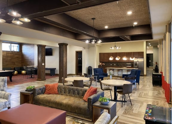 a lobby with couches and tables and chairs and a kitchen at Retreat Apartments in Williston, ND 
