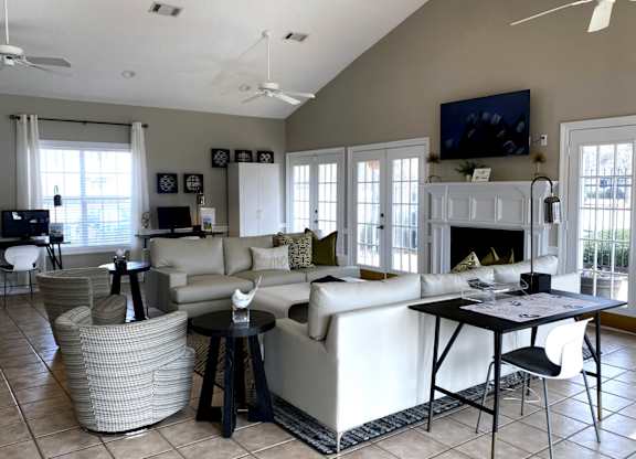 A living room with a white couch, a black coffee table, and a television on the wall.