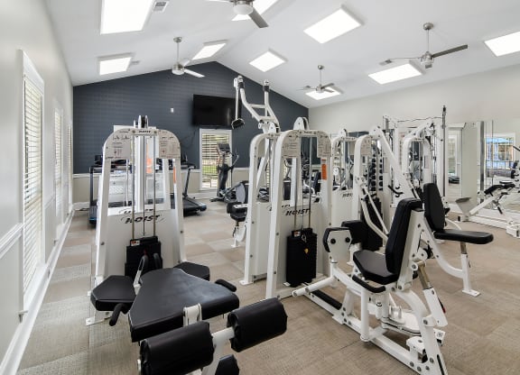 a gym with cardio equipment and weights in a building with windows at Bridgewater Apartment Homes, Brandon