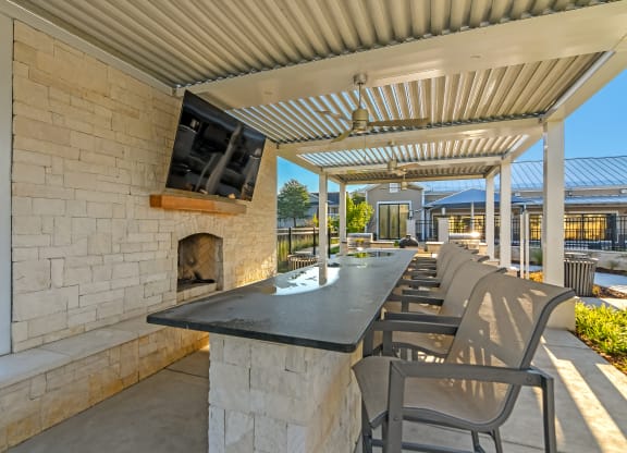 the outdoor patio has a fireplace and a long table with chairs at Crossgates Apartment Homes, Starkville, MS 39759