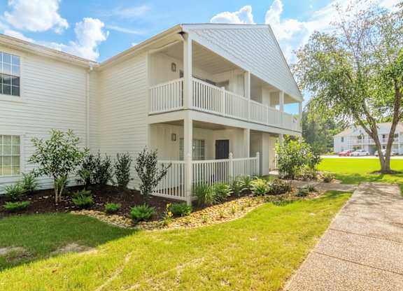 A white two-story house with a balcony on the second floor.