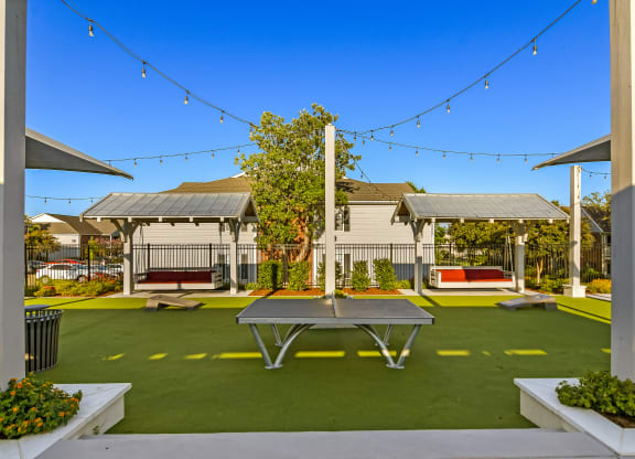 a ping pong table sits in the middle of a courtyard with picnic tables at Crossgates Apartment Homes, Starkville, MS 39759