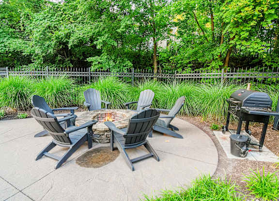 A fire pit surrounded by chairs in a backyard.