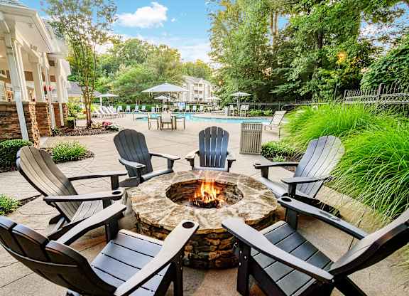 A fire pit surrounded by chairs in a backyard setting.
