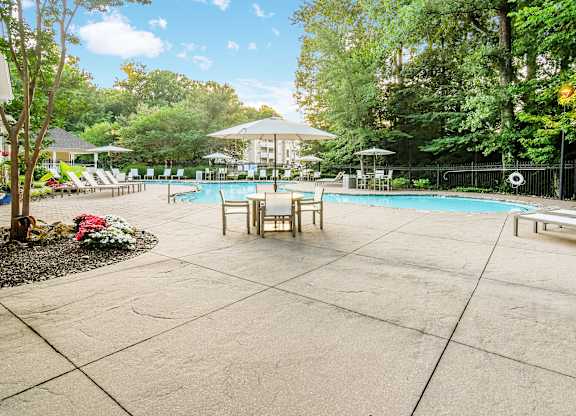 A pool surrounded by trees and umbrellas.