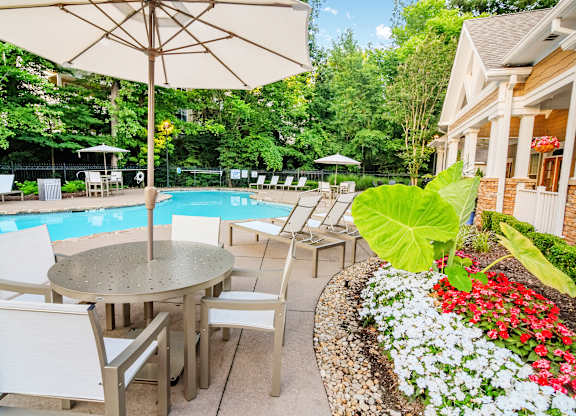 A patio with a table and chairs overlooking a pool.