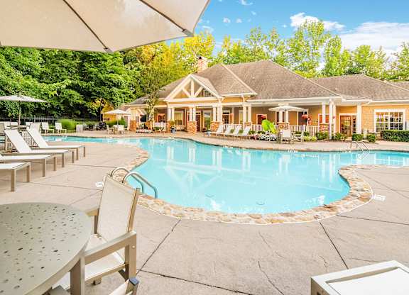 A pool area with a house in the background.