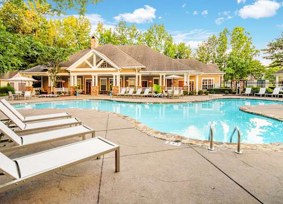 a walkway leading to a park with a playground and trees at Crossgates Apartment Homes, Starkville, MS 39759