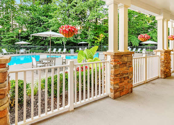 A pool area with a white fence and red flowers.