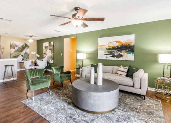 a living room with green walls and a white couch and green chairs at Crossgates Apartment Homes, Starkville, MS