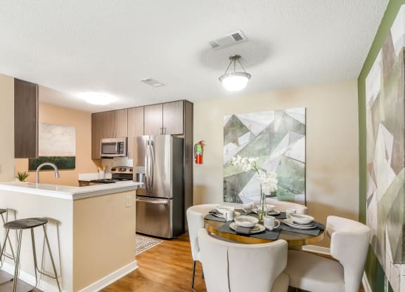 an open kitchen and dining room with stainless steel appliances and a table and chairs at Crossgates Apartment Homes, Starkville, MS